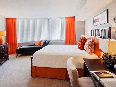 A bedroom with a large bed and a black couch.