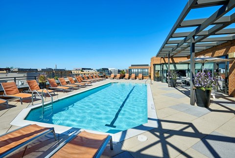 A large outdoor swimming pool with lounge chairs and a building in the background.