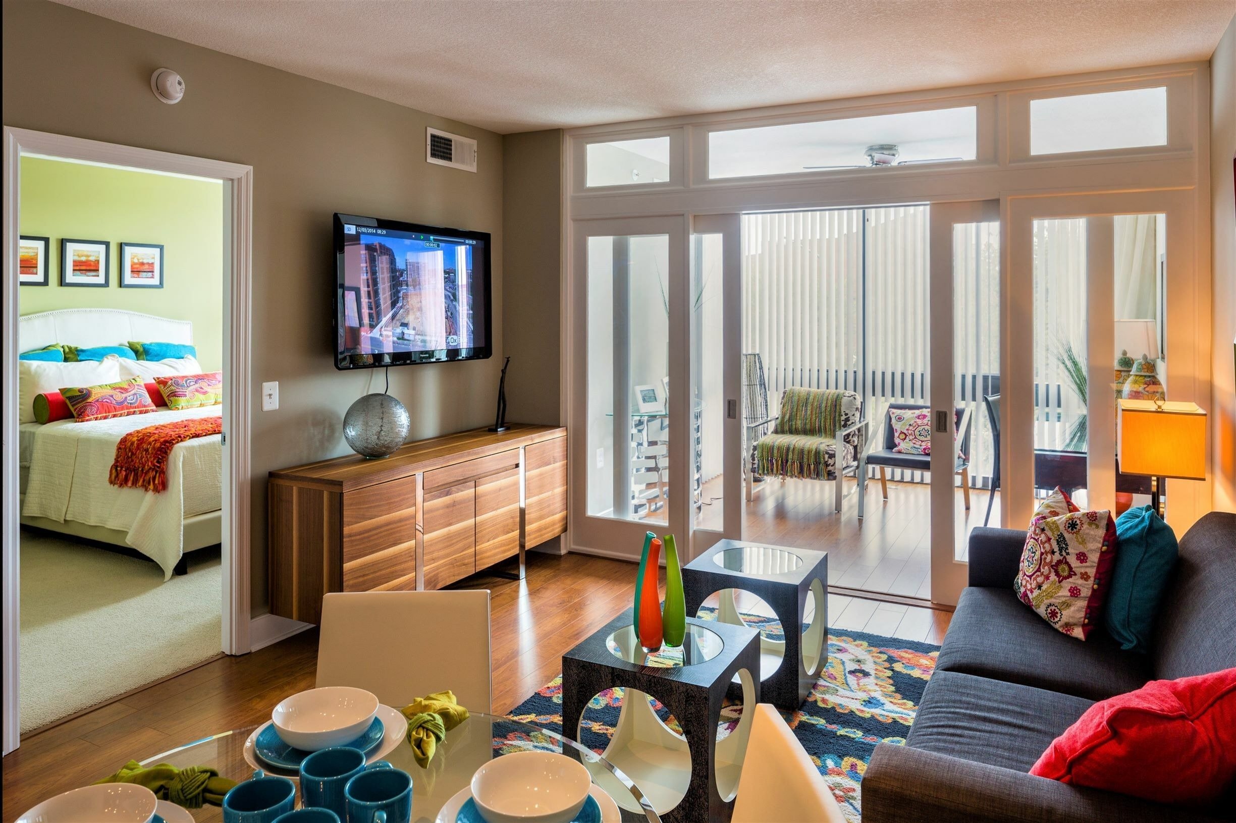 A living room with a couch, a television, and a glass table with various objects on it.