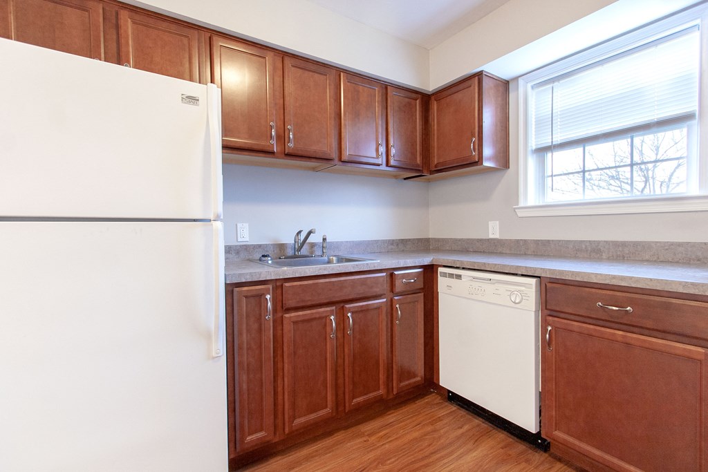 an empty kitchen with wooden cabinets and a white refrigerator