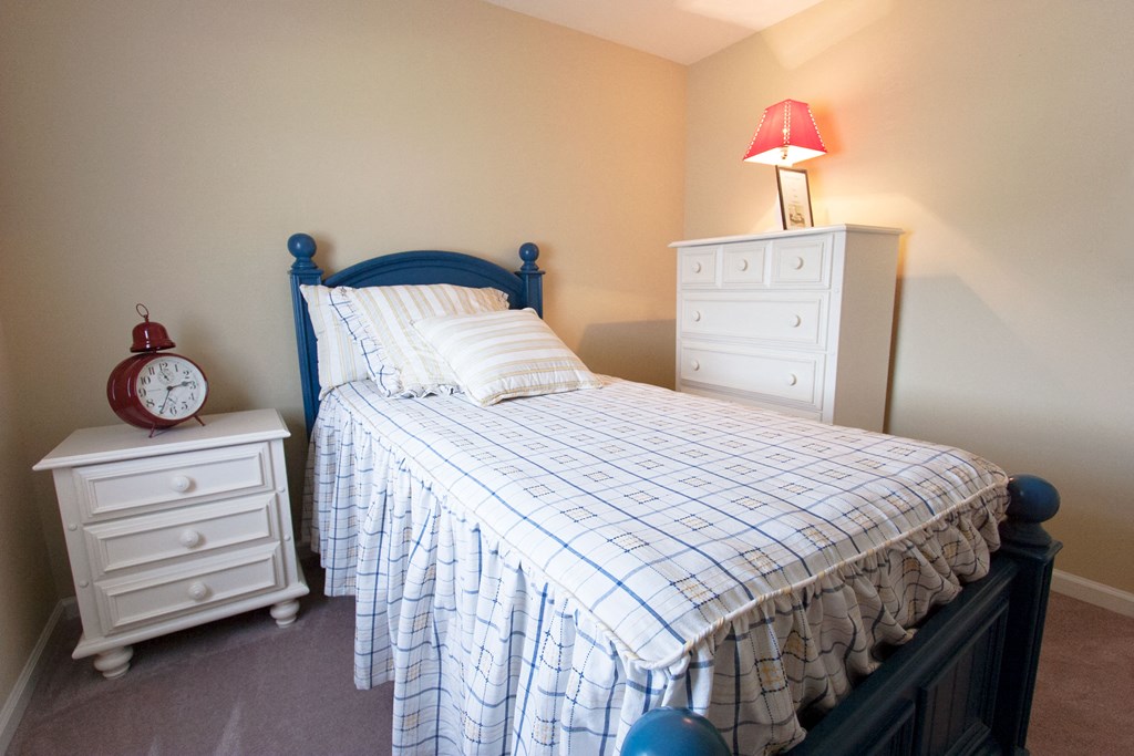 a bedroom with a bed and two dressers and a clock