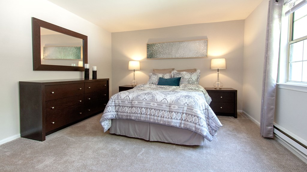 a bedroom with a bed and two dressers and a window