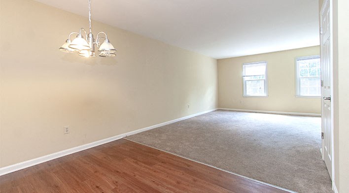 an empty living room with a hard wood floor and a chandelier