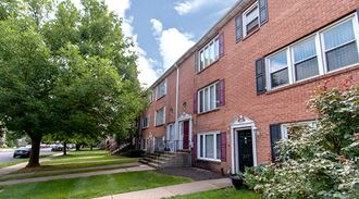 a red brick apartment building with a lawn and trees