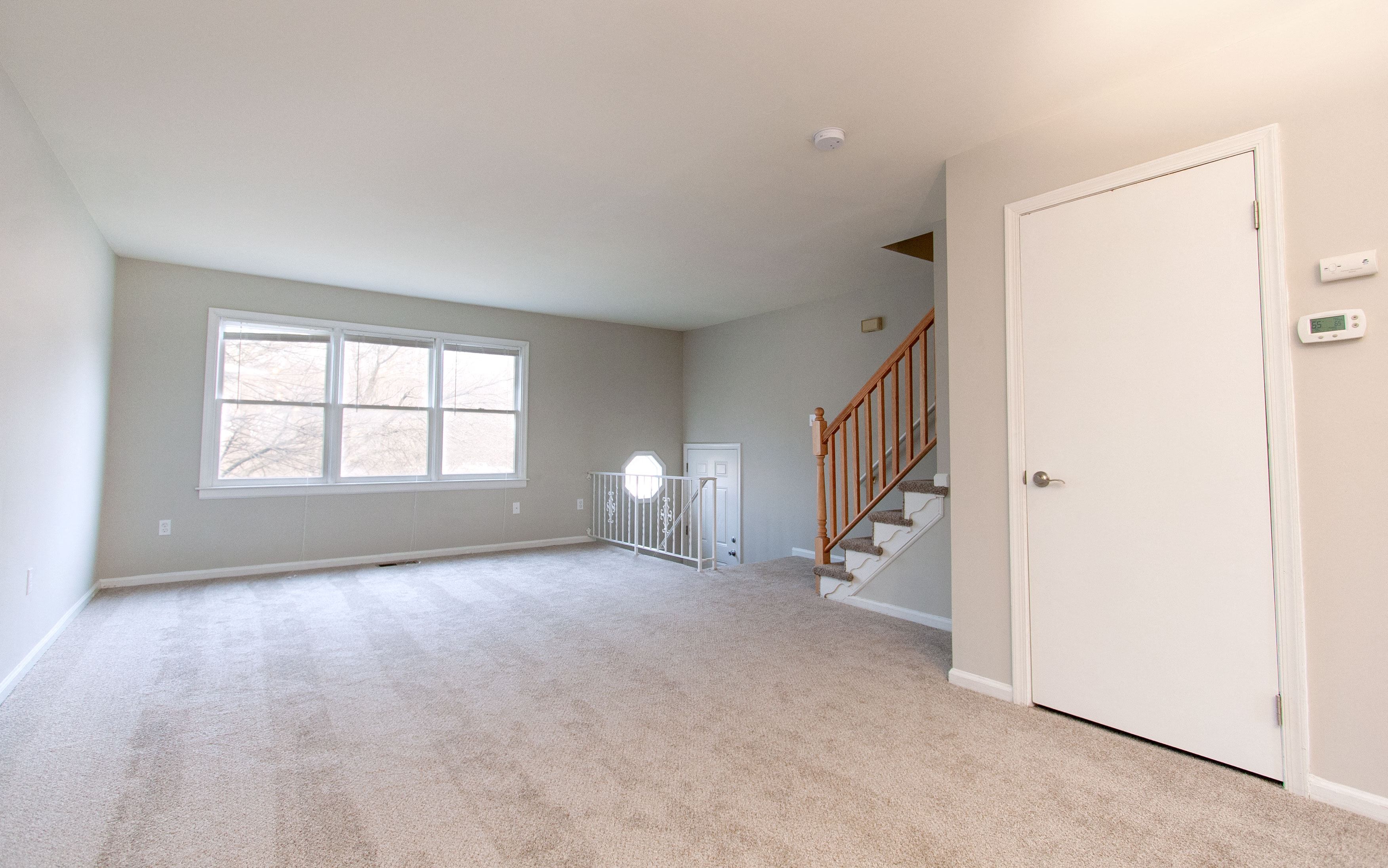 an empty living room with a staircase and a large window