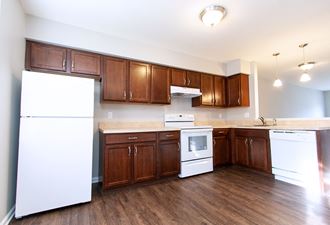 an empty kitchen with white appliances and wooden cabinets