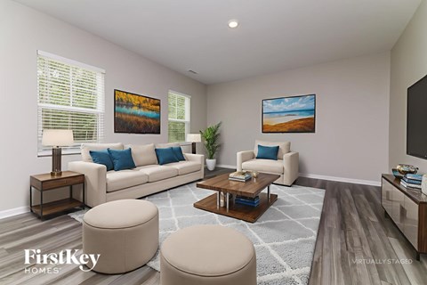 A living room with a white couch, a coffee table, and two paintings on the wall.