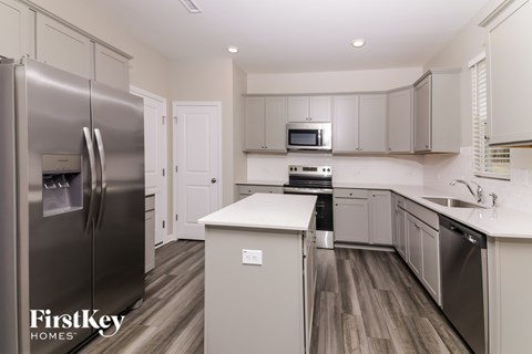 A kitchen with a stainless steel refrigerator and wooden floors.