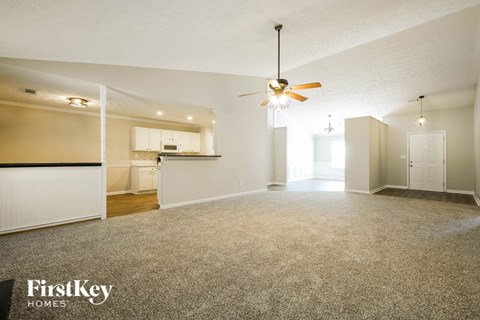 A spacious room with a ceiling fan and carpeted floor.