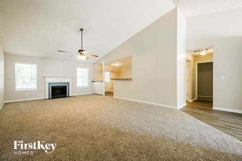 A spacious living room with a fireplace and a ceiling fan.