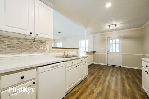 A kitchen with white cabinets and a wooden floor.