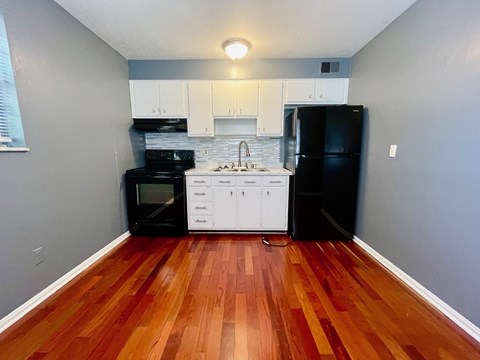 A kitchen with a black fridge and white cabinets.