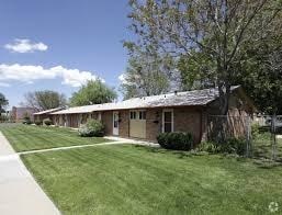 A small building with a brown roof is surrounded by a green lawn.