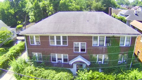 A red brick house with a grey roof and a white door.