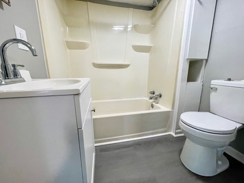 A white bathroom with a toilet, sink, and bathtub.