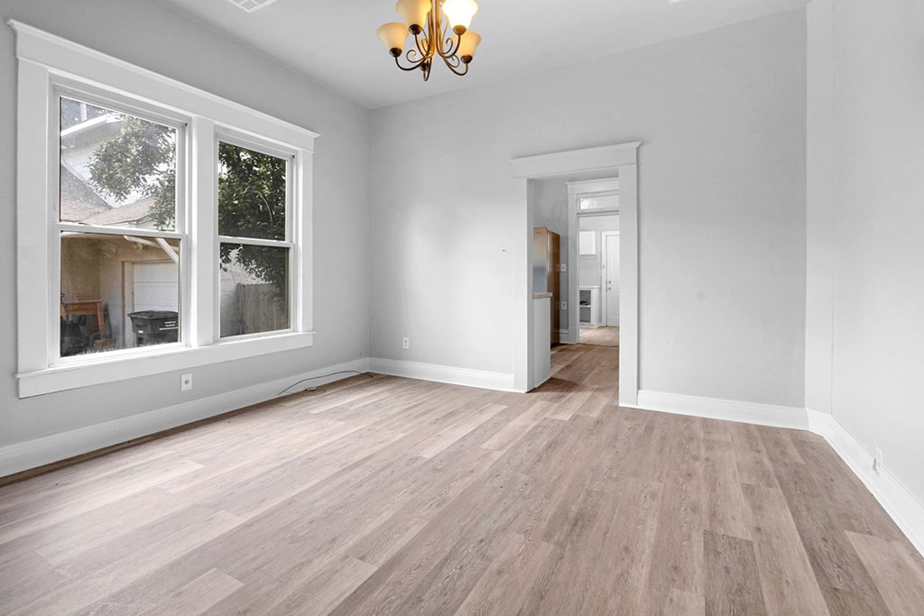 A room with a chandelier, a window, and a door.