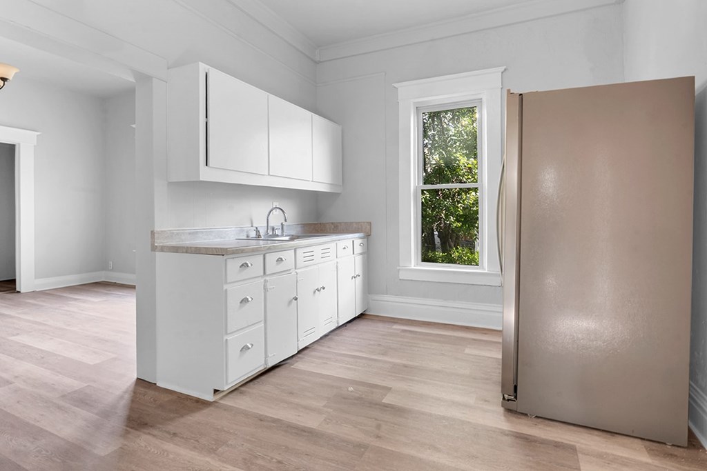 A kitchen with white cabinets and a window.