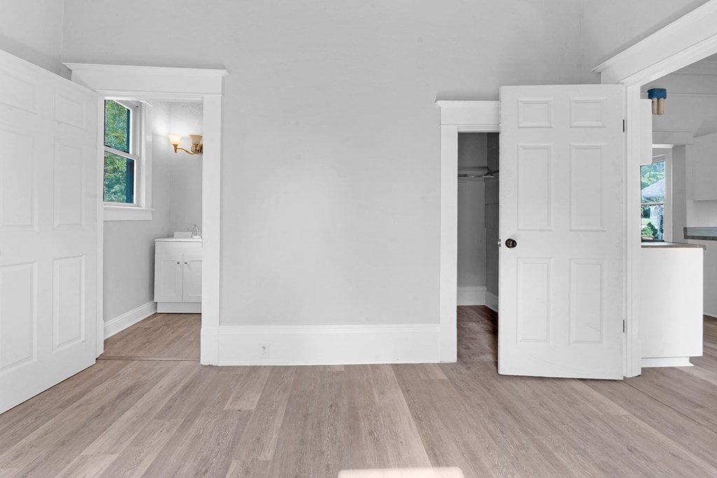 A white room with a wooden floor and a window.