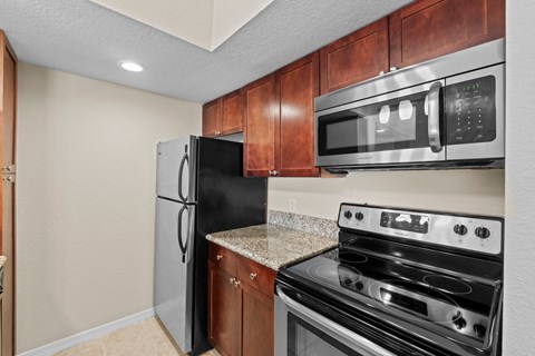 A kitchen with a black fridge, microwave and stove.