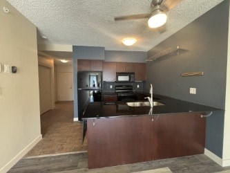 A kitchen with a black counter top and a fan on the ceiling.