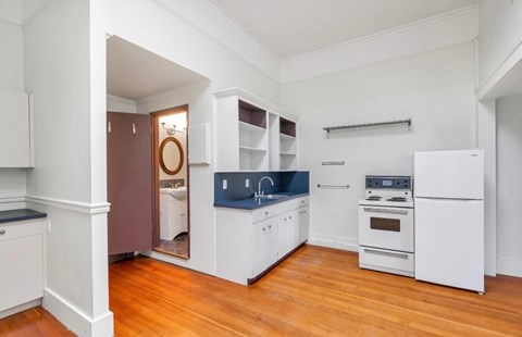 A kitchen with white cabinets and a wooden floor.