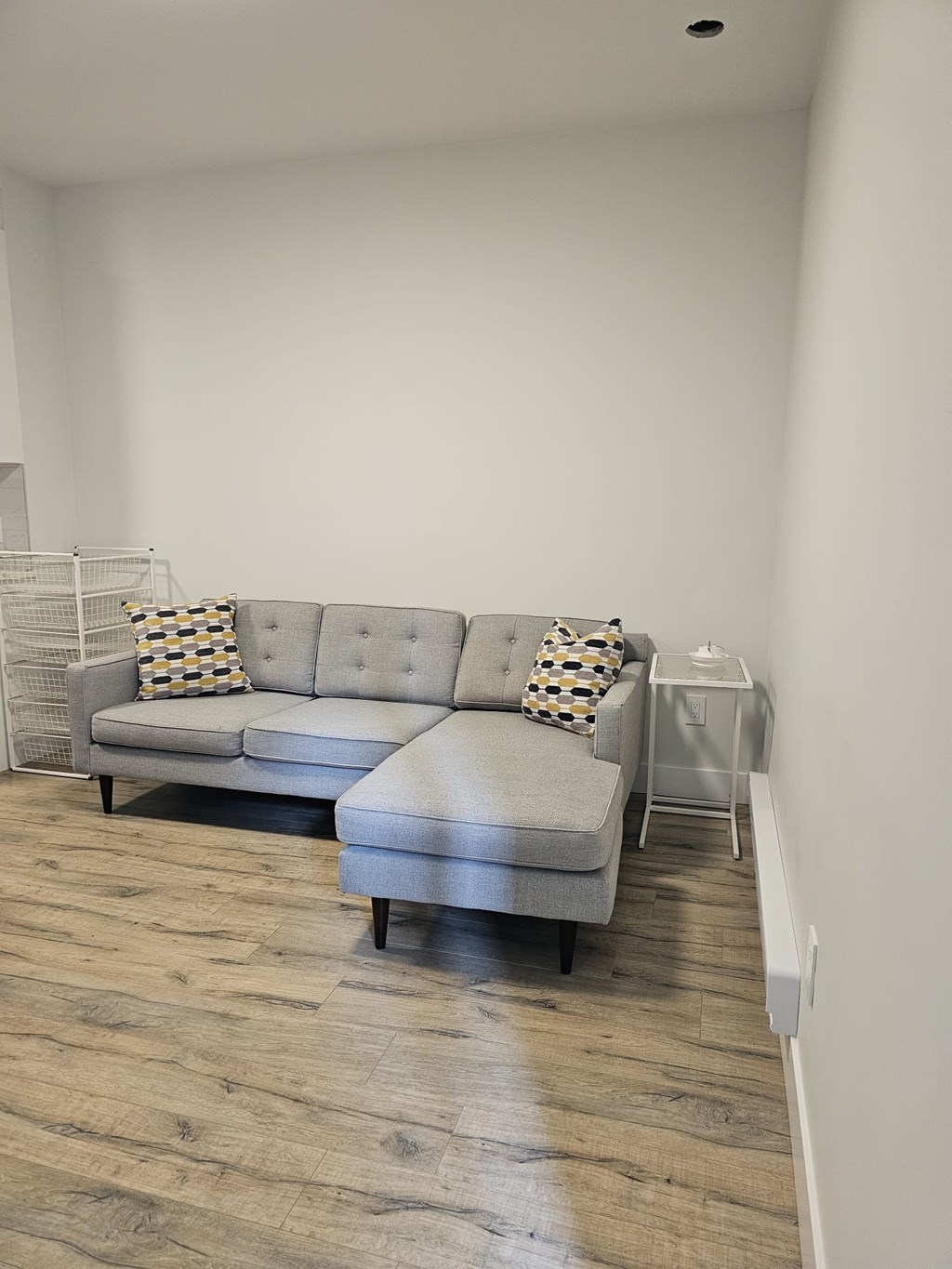 A grey couch with a pillow on it in a room.