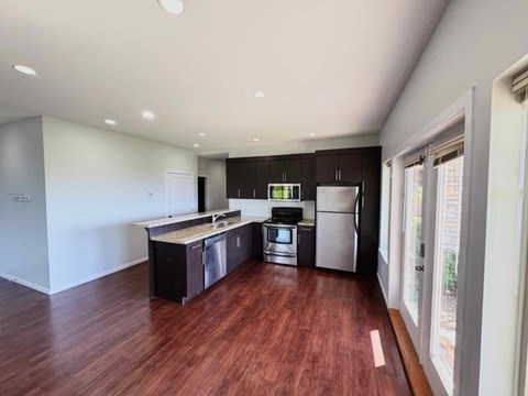 A kitchen with dark wood floors and stainless steel appliances.