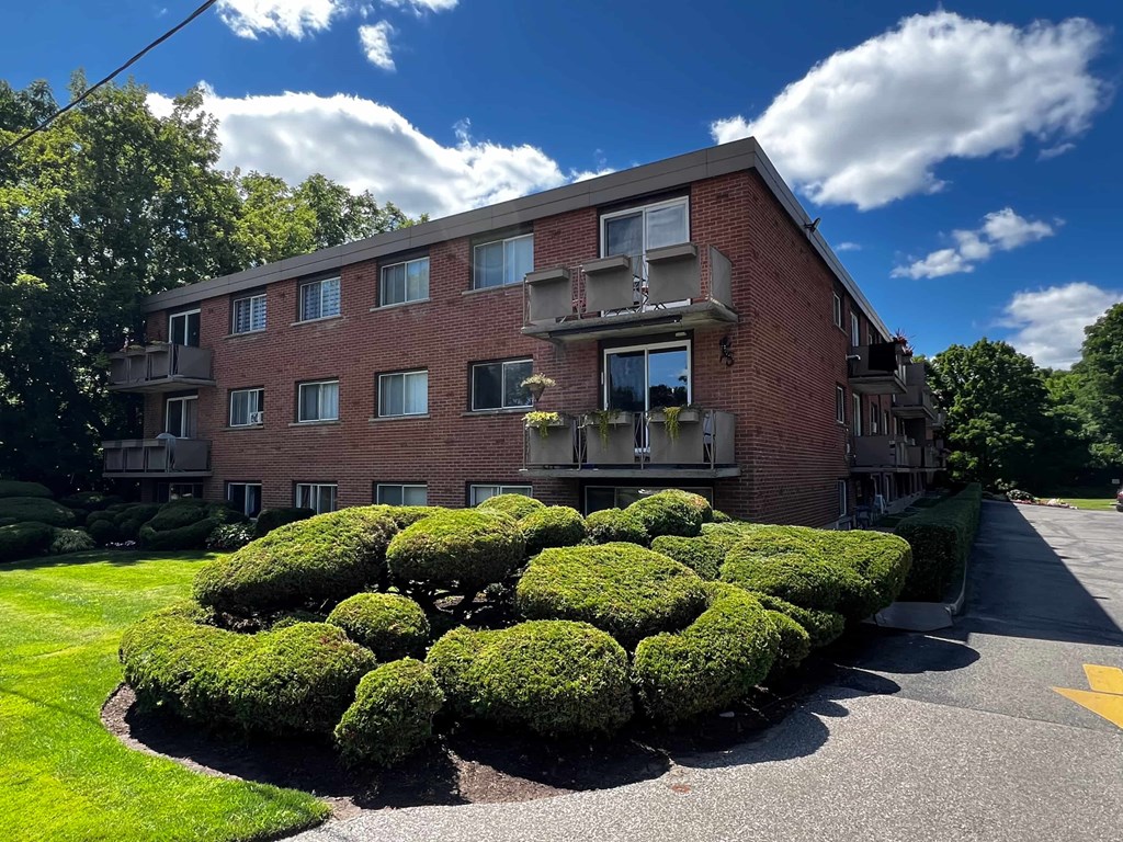 A red brick building with a green lawn in front.