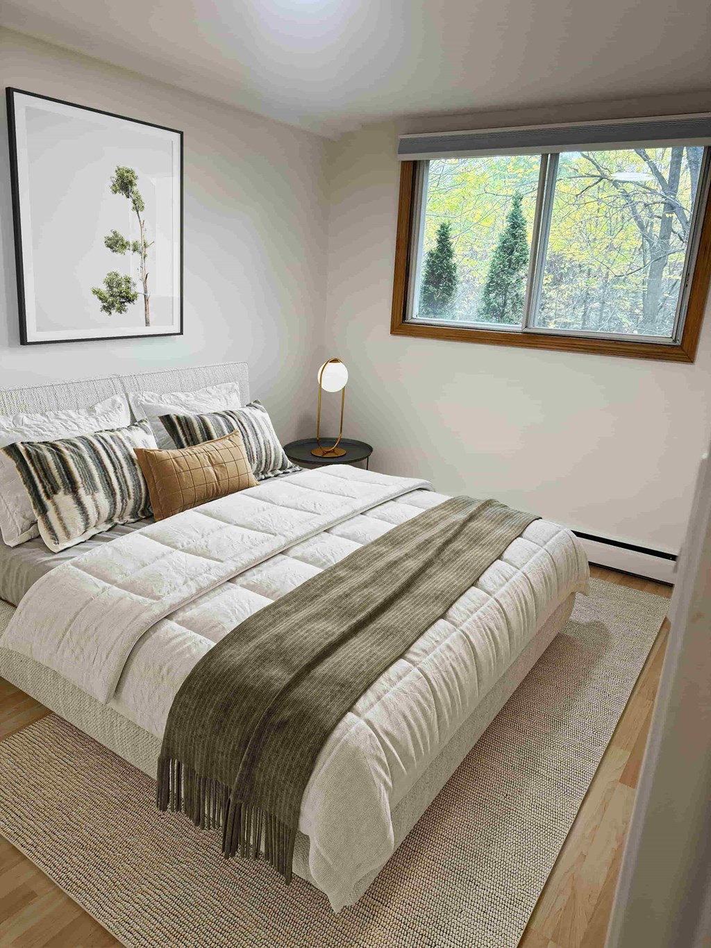 A bedroom with a large bed and a window showing trees outside.
