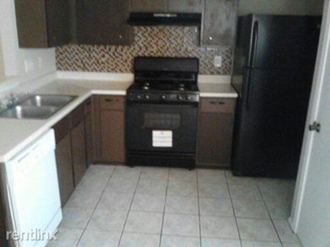 A black stove top oven in a kitchen with a white dishwasher and black refrigerator.