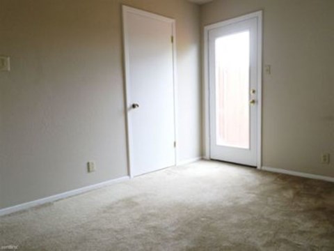 A room with two white doors and carpeted flooring.
