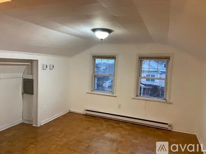A room with wooden floors and two windows.