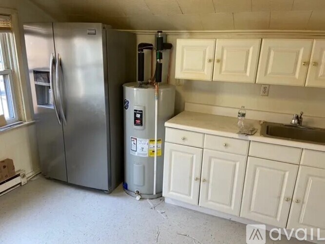 A kitchen with a refrigerator, a water heater, and a sink.