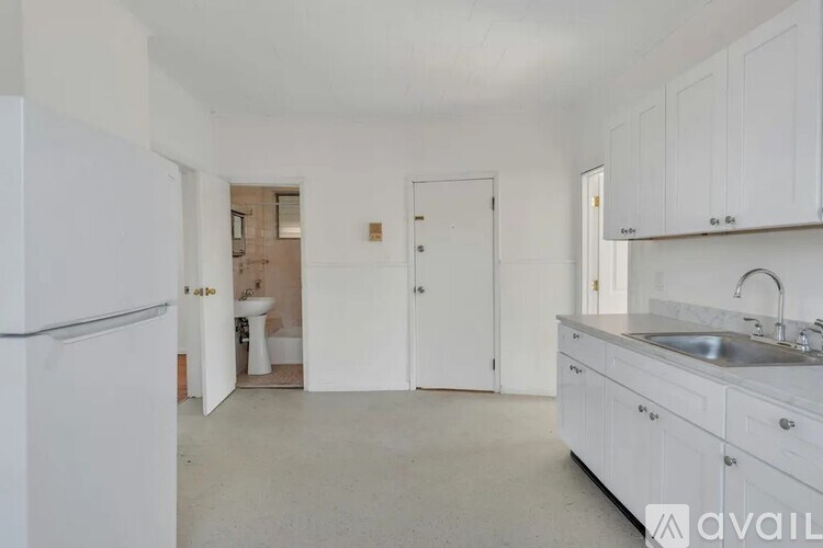 A kitchen with white cabinets and a refrigerator.