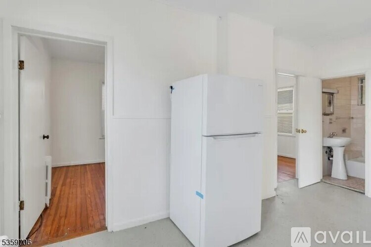 A white refrigerator is in a room with a wooden floor and a door.