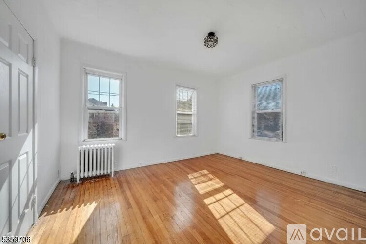 A room with wooden floors and white walls, with a window and a picture on the wall.