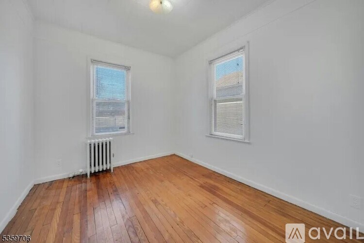 A room with wooden floors and two windows.