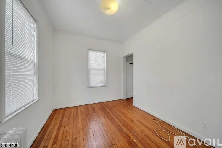 A room with wooden floors and white walls, with a window on the left side.