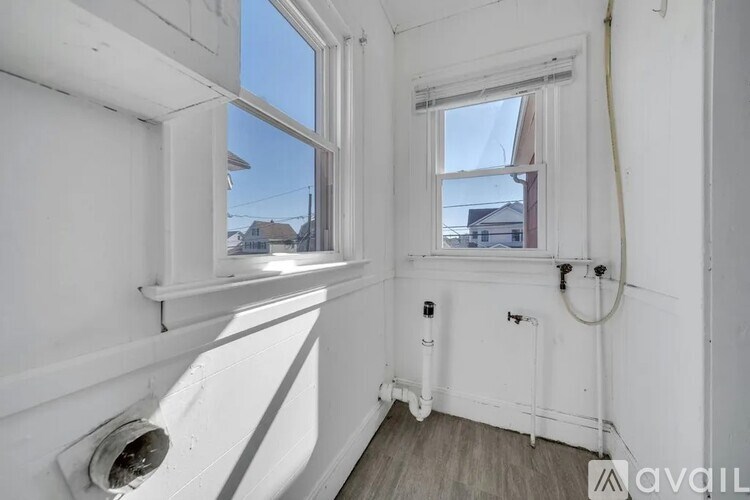 A white room with a window and a pipe running along the wall.