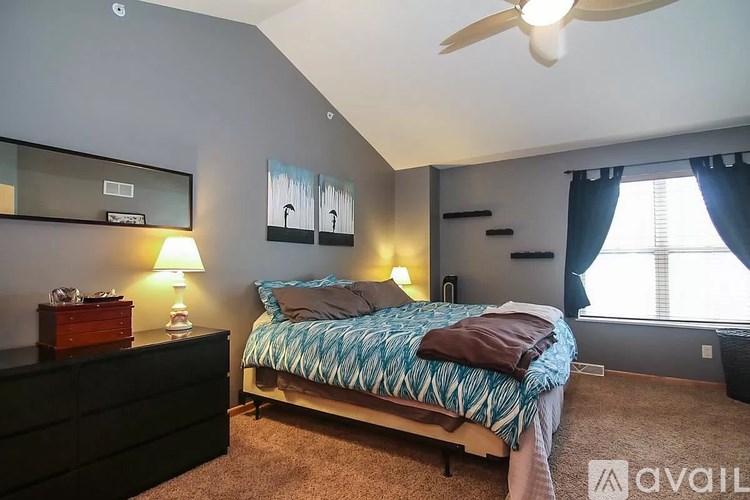 A bedroom with a bed, dresser, and ceiling fan.
