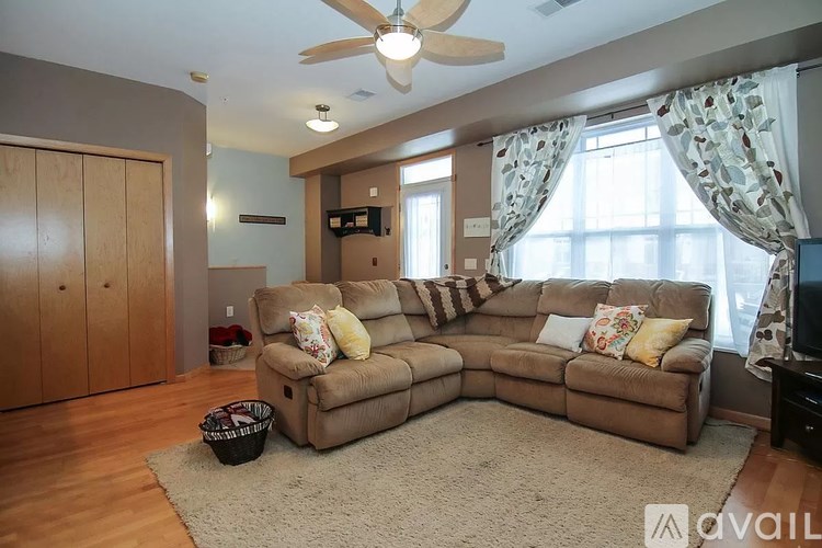 A living room with a large sectional sofa and a ceiling fan.