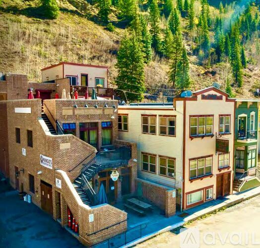 A building with a sign that says "AVAILABLE" in front of a mountain.