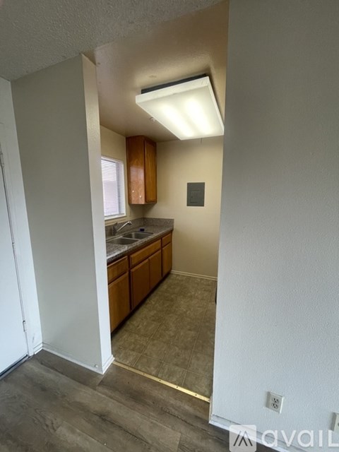 A kitchen area with a refrigerator, cabinets, and a window.