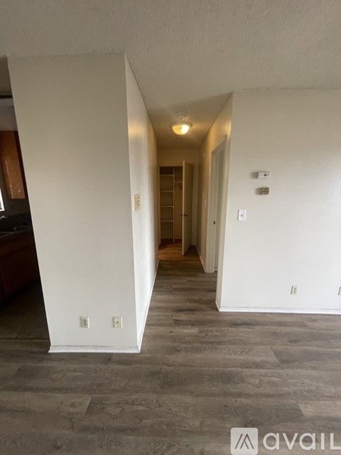 A hallway with a white wall and a door at the end.
