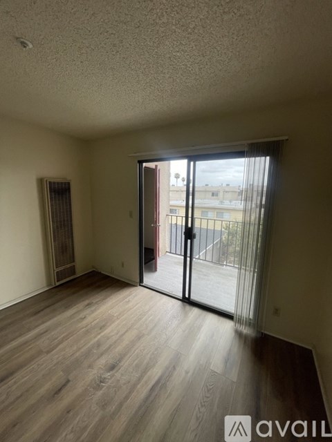 A room with wooden flooring and a sliding glass door leading to a balcony.