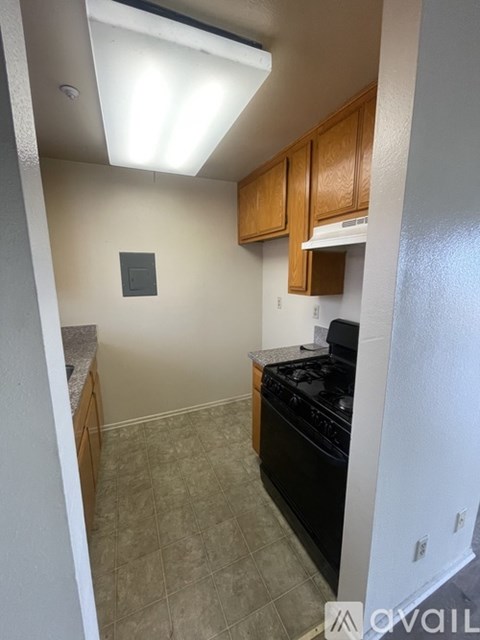 A kitchen with a black stove top oven and wooden cabinets.