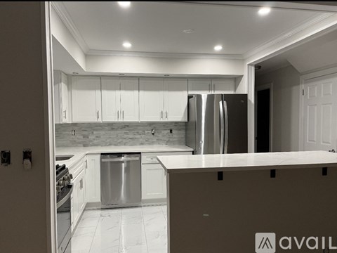 A modern kitchen with white cabinets and a stainless steel refrigerator.