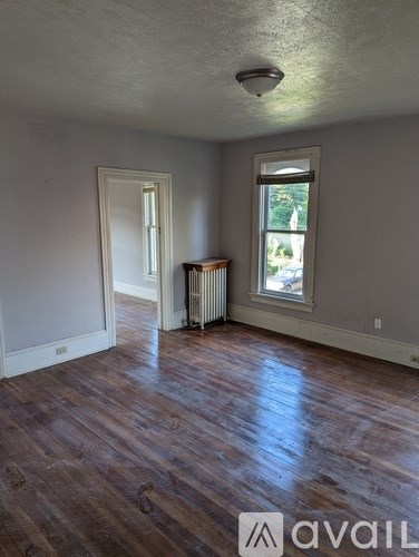 A room with wooden floors and a window with a view of trees outside.