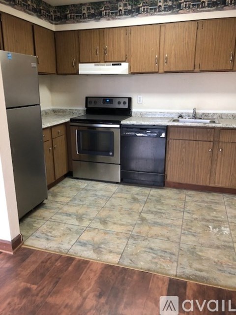 A kitchen with a refrigerator, oven, and dishwasher.