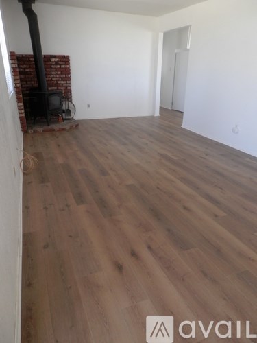 A room with a wood floor and a brick fireplace.